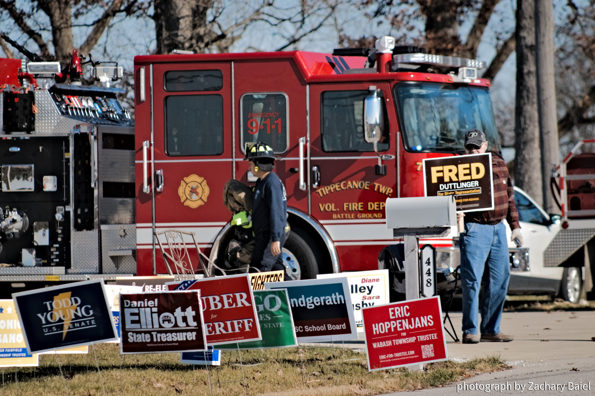 A firefighter returns from a call, political supporter stands with a sign outside of the polling place on Election Day in Tippecanoe County | November 2022