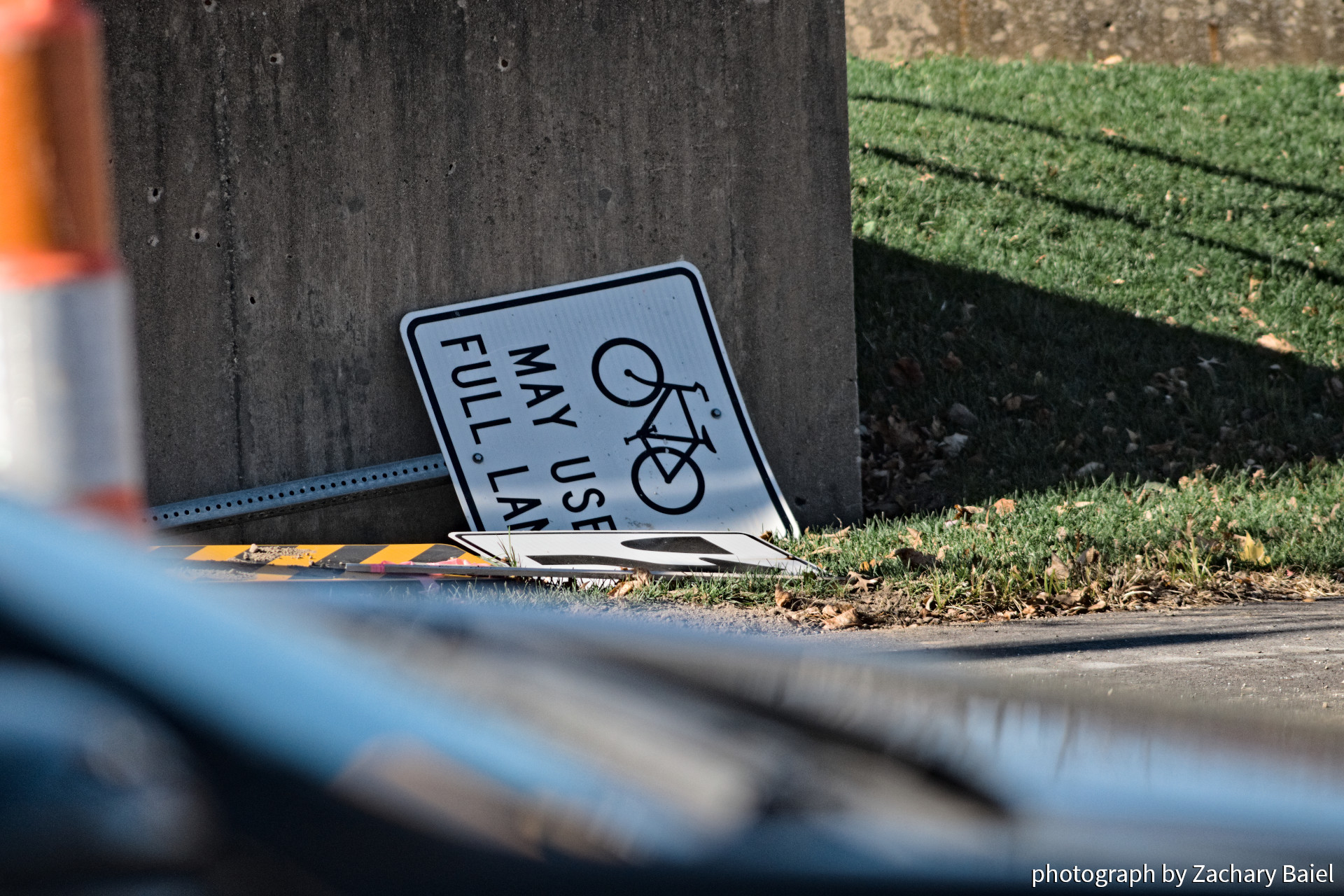 Discarded road sign, "Bicycles May Use Full Lane", on the side of Salisbury St. West Lafayette Indiana | November 2022