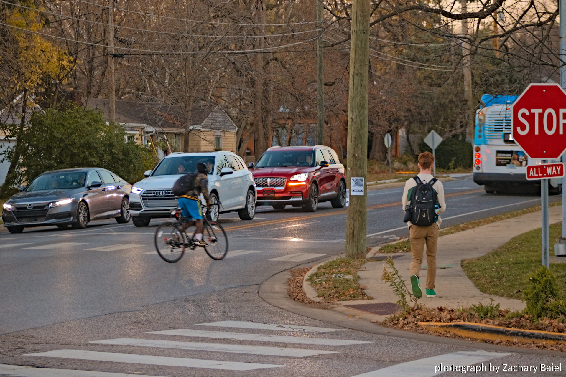 Intersection of Robinson and Salisbury just before sunset, with a bicyclist, pedestrian, bus, and cars | November 2022